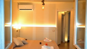A hotel room with a bed, a bedside table, a lamp, and an air conditioning unit. - Villa Paglianiti - Your Family Residence (Briatico)
