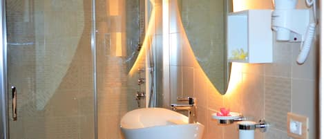 A modern bathroom with a glass shower enclosure, a freestanding white sink, and a hairdryer mounted on the wall.