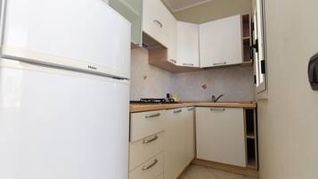 A compact kitchen with white cabinets, a Haier refrigerator, and a small countertop.