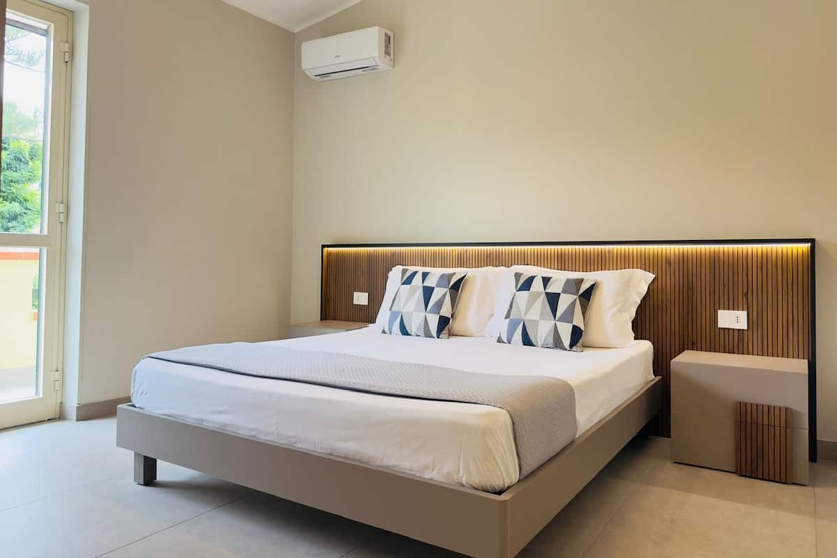 Quarto moderno com cama, mesas de cabeceira e uma janela.