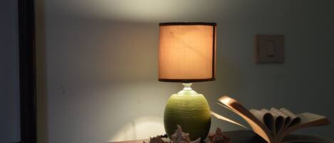 Une table avec une lampe verte, un livre ouvert et des coquillages.