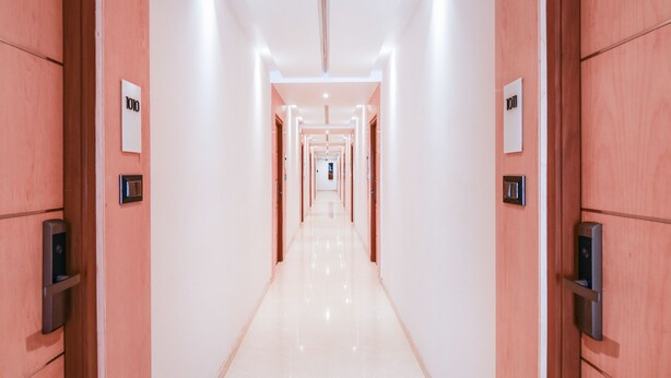 A long, well-lit hallway with doors on either side, leading to individual rooms. - Treebo Vinayak Inn (Coimbatore)