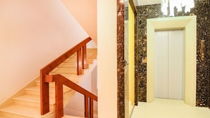 A staircase with wooden handrails and a white door with a marble wall. - Treebo Vinayak Inn (Coimbatore)