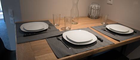 A dining table set with plates, cutlery, and glasses, with a vase and candle holder on the table.