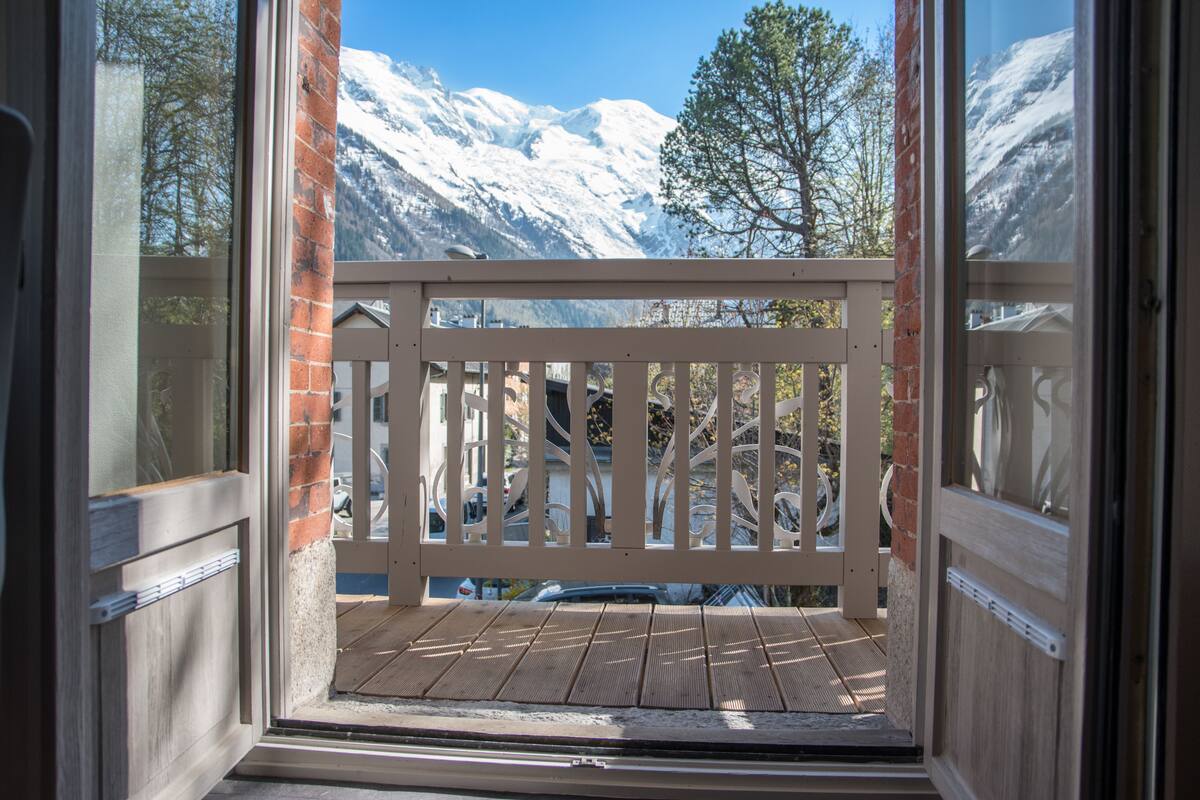 A balcony with a view of snow-covered mountains and trees.