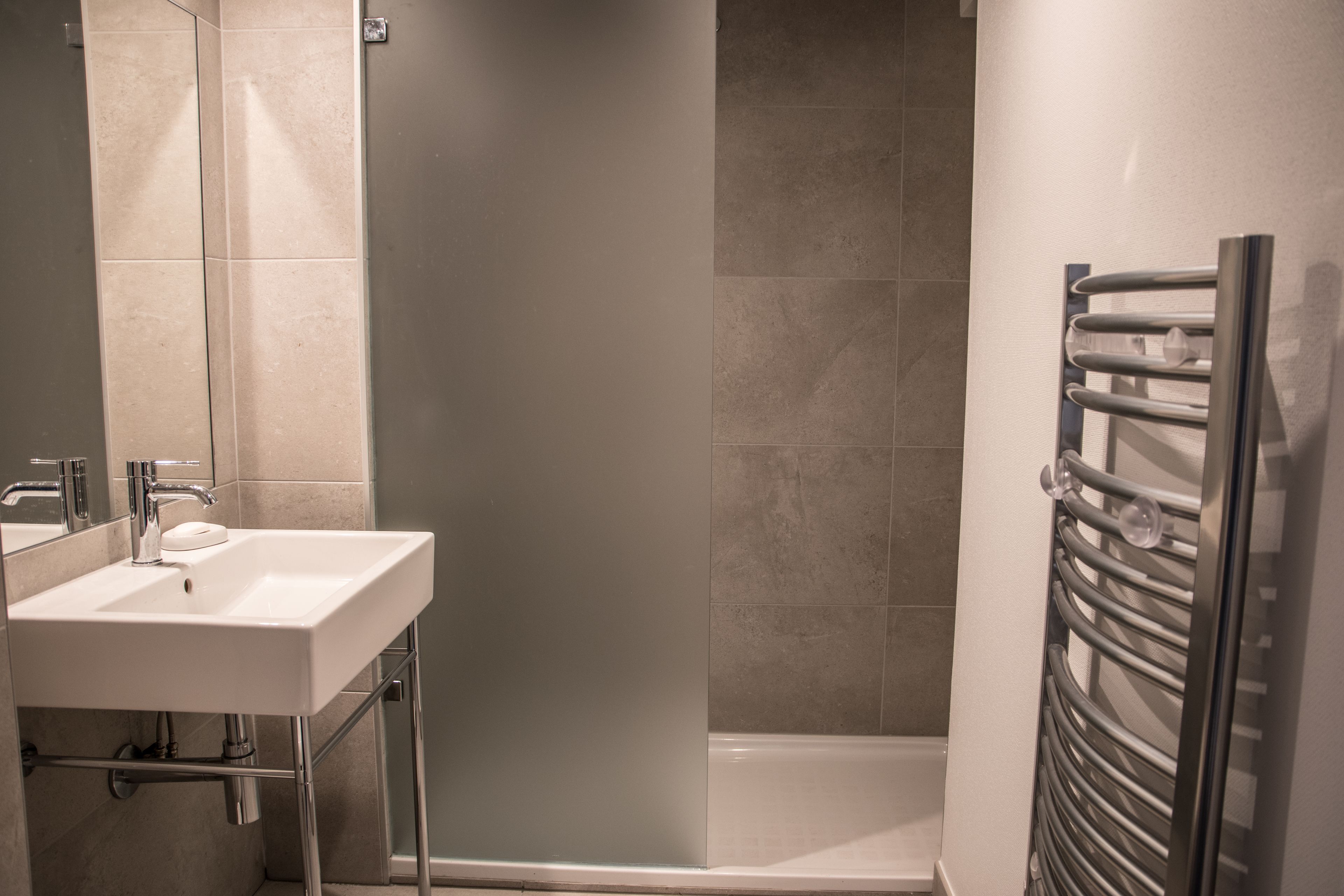 A modern bathroom with a white sink, a mirror, and a shower enclosure.