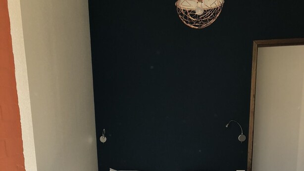A small, narrow room with a bed, a dark wall, and a single light fixture. - Aiguille Verte & spa (Chamonix-Mont-Blanc)