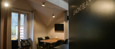 Une pièce comprenant une table à manger, des chaises, un canapé rouge et un mur noir sur lequel est inscrit le texte « LE MONT BLANC ».