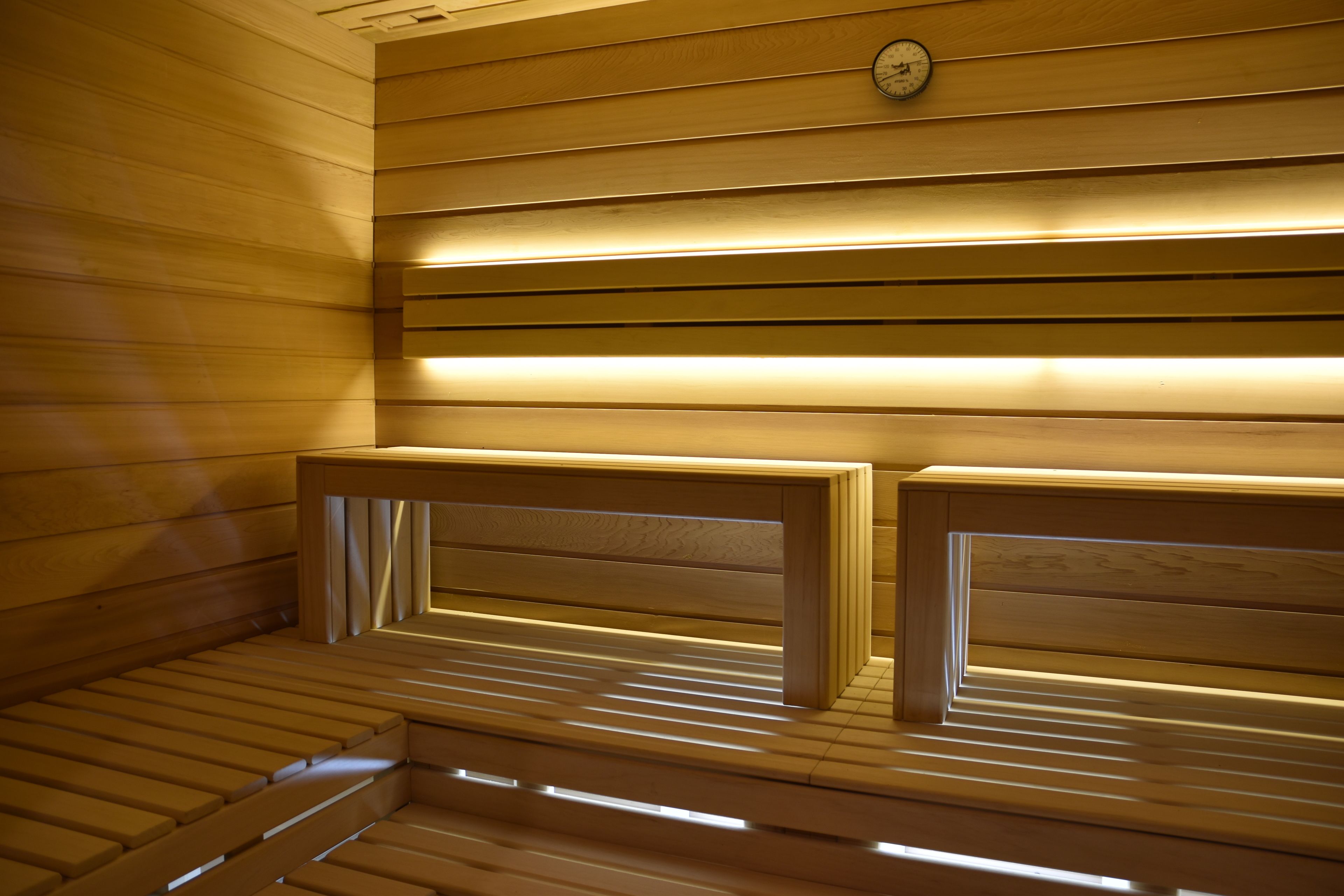 Un sauna avec des bancs en bois et une horloge au mur.