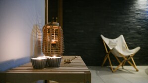 Una mesa de madera con velas, un farolillo y una silla.