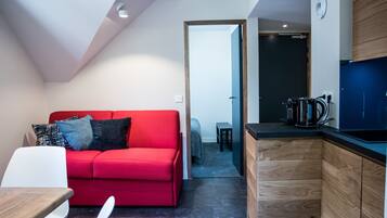 A modern living space with a red sofa, a wooden cabinet, and a kitchen area.