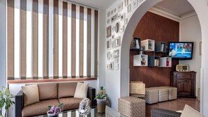A modern living room with a glass coffee table, sofas, and a television. - Hotel Azzurra (Pietrasanta)