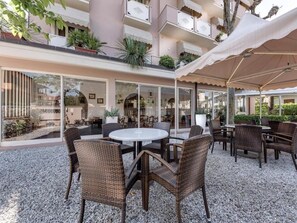 Un espace extérieur aménagé en terrasse, avec des meubles en osier, une table ronde et un coin salon abrité.