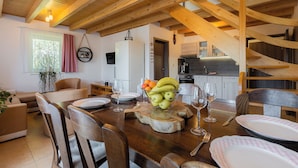 A dining area with a wooden table set for a meal, surrounded by chairs. - Apartmány Nad Rybníky (Horni Plana)