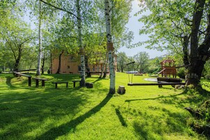 Un parque con mesas de picnic, columpios y un área de juegos.