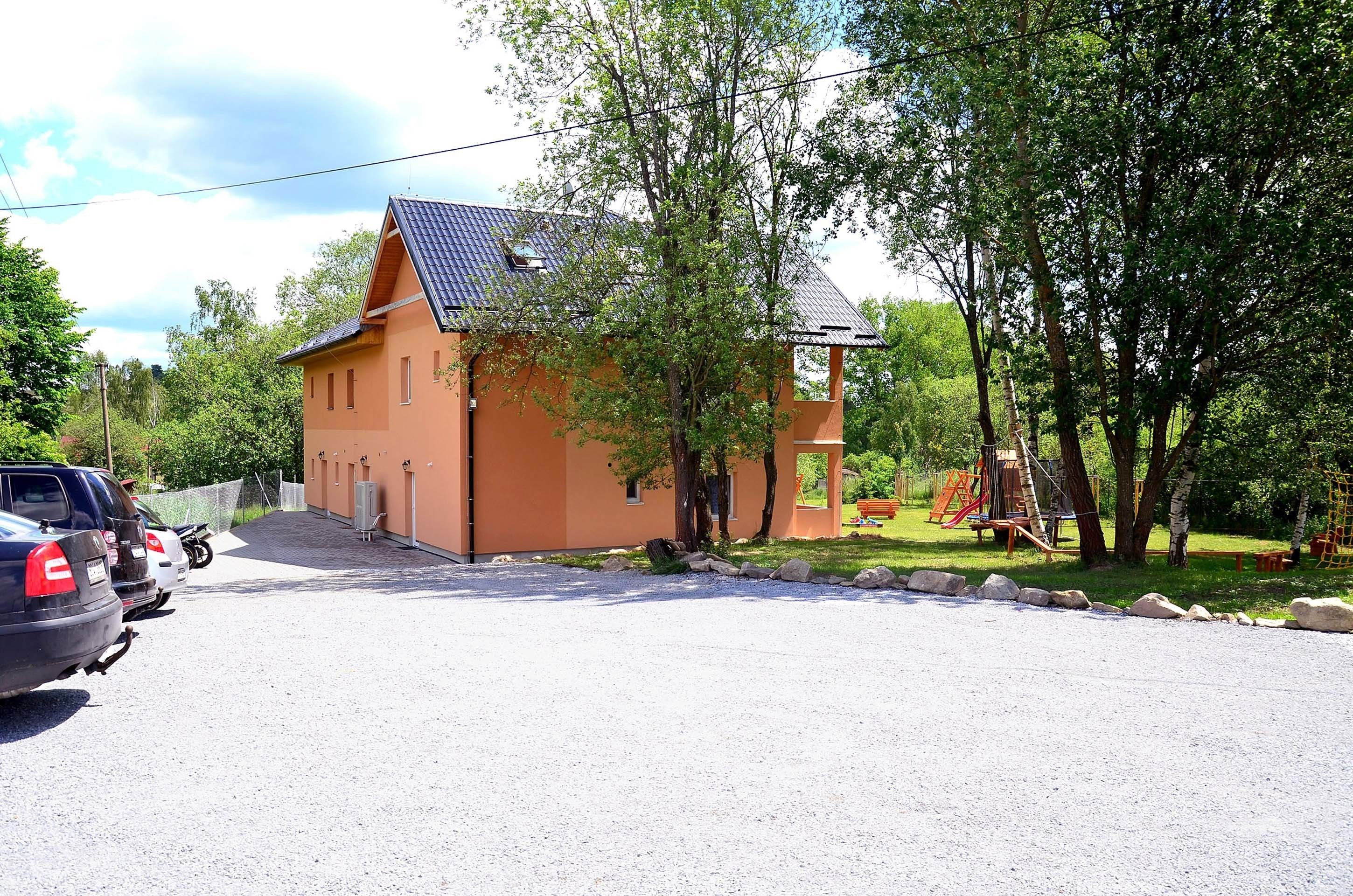 A two-story building with a sloped roof, a small attached structure, and a playground with a slide and climbing frame.