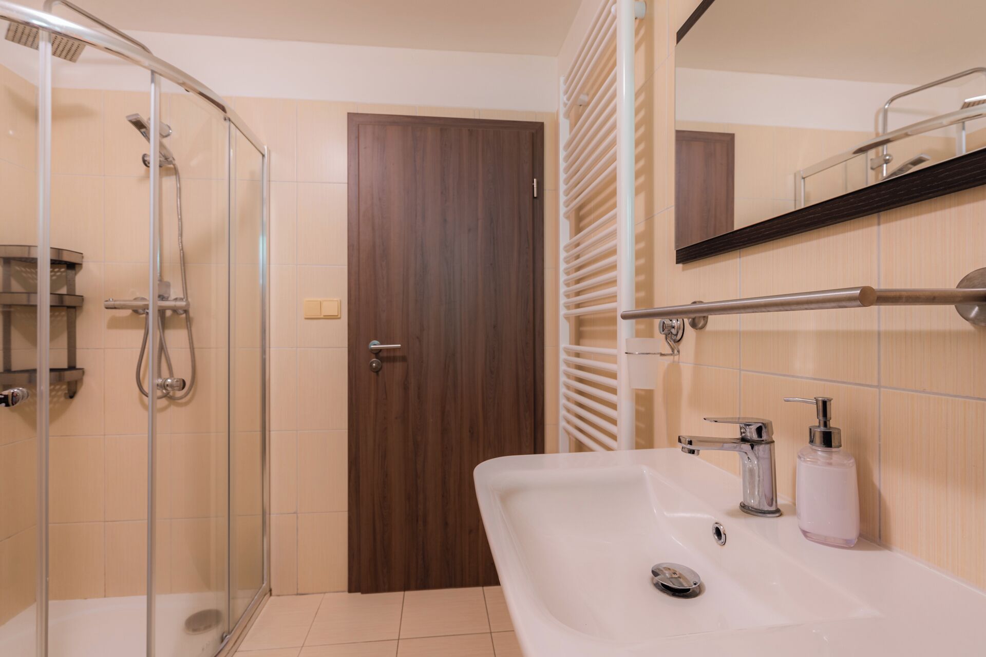 A bathroom with a glass shower enclosure, a sink with a mirror, and a towel rack.