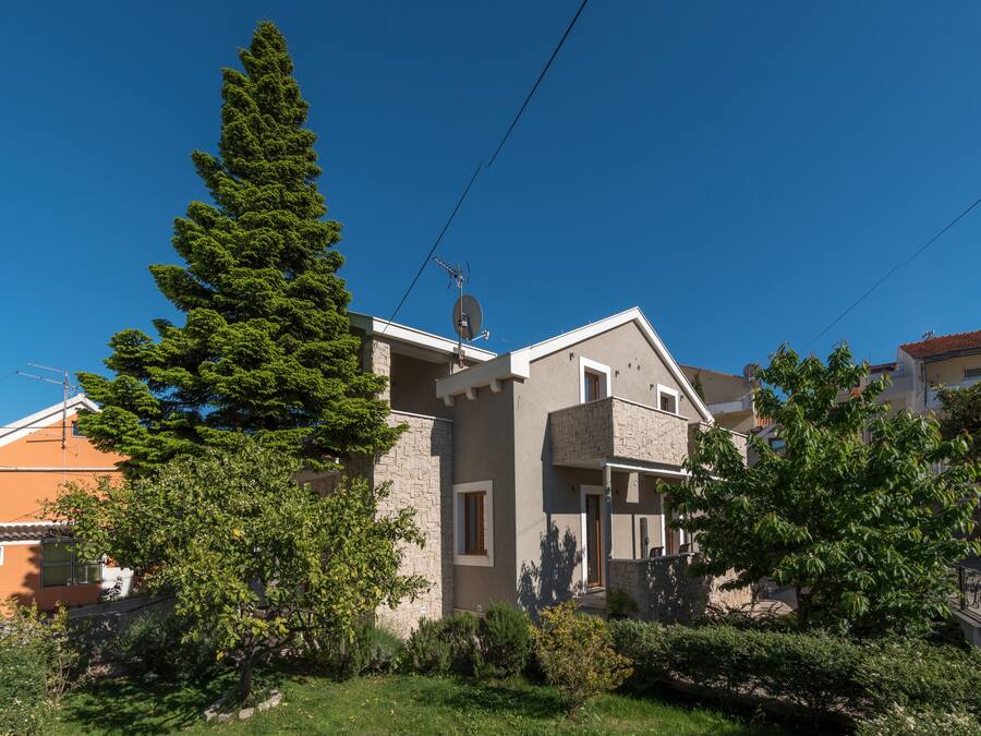 A modern two-story house with a stone facade, a satellite dish, and a well-maintained garden.