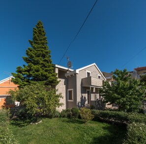 Una casa moderna de dos pisos con fachada de piedra, antena parabólica y un jardín bien cuidado.