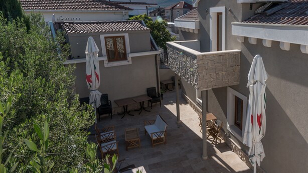 An outdoor patio with seating and umbrellas, surrounded by greenery and buildings. - Villa Lucica Trogir (Trogir)