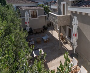 An outdoor patio with seating and umbrellas, surrounded by greenery and buildings. - Villa Lucica Trogir (Trogir)