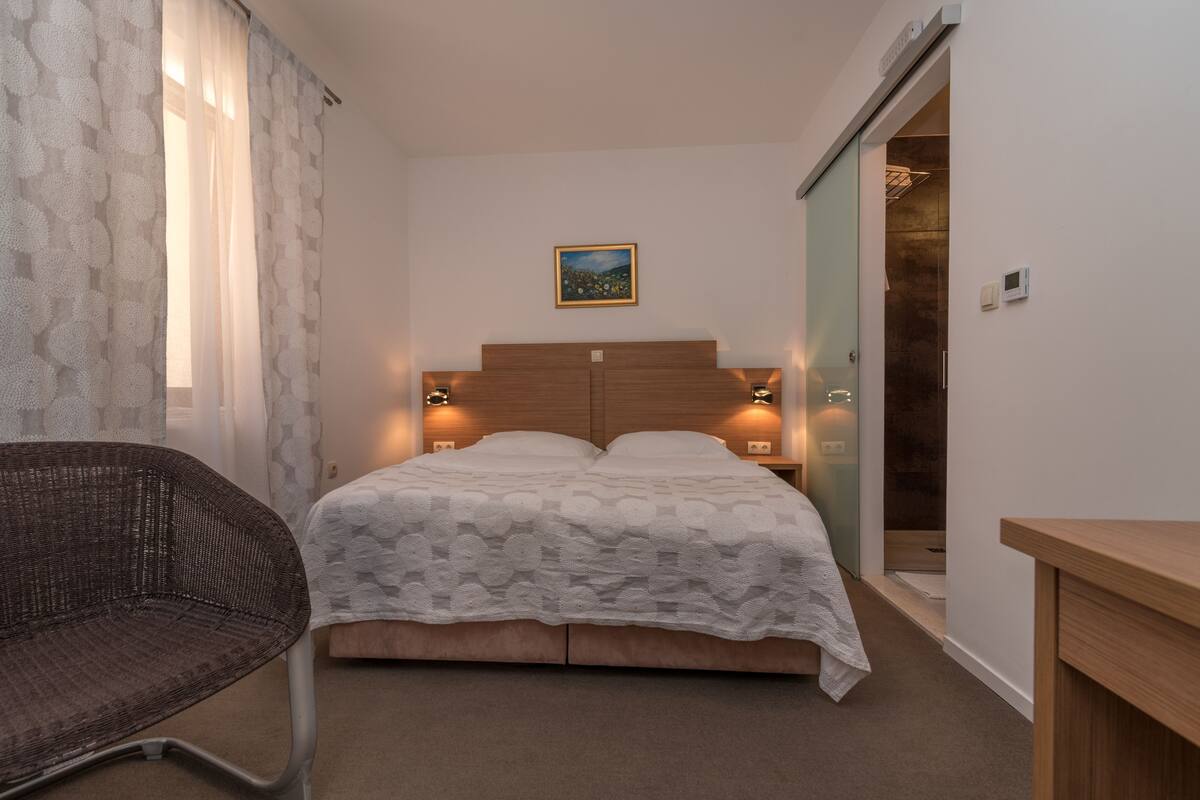 A bedroom with a bed, a chair, and a painting on the wall.