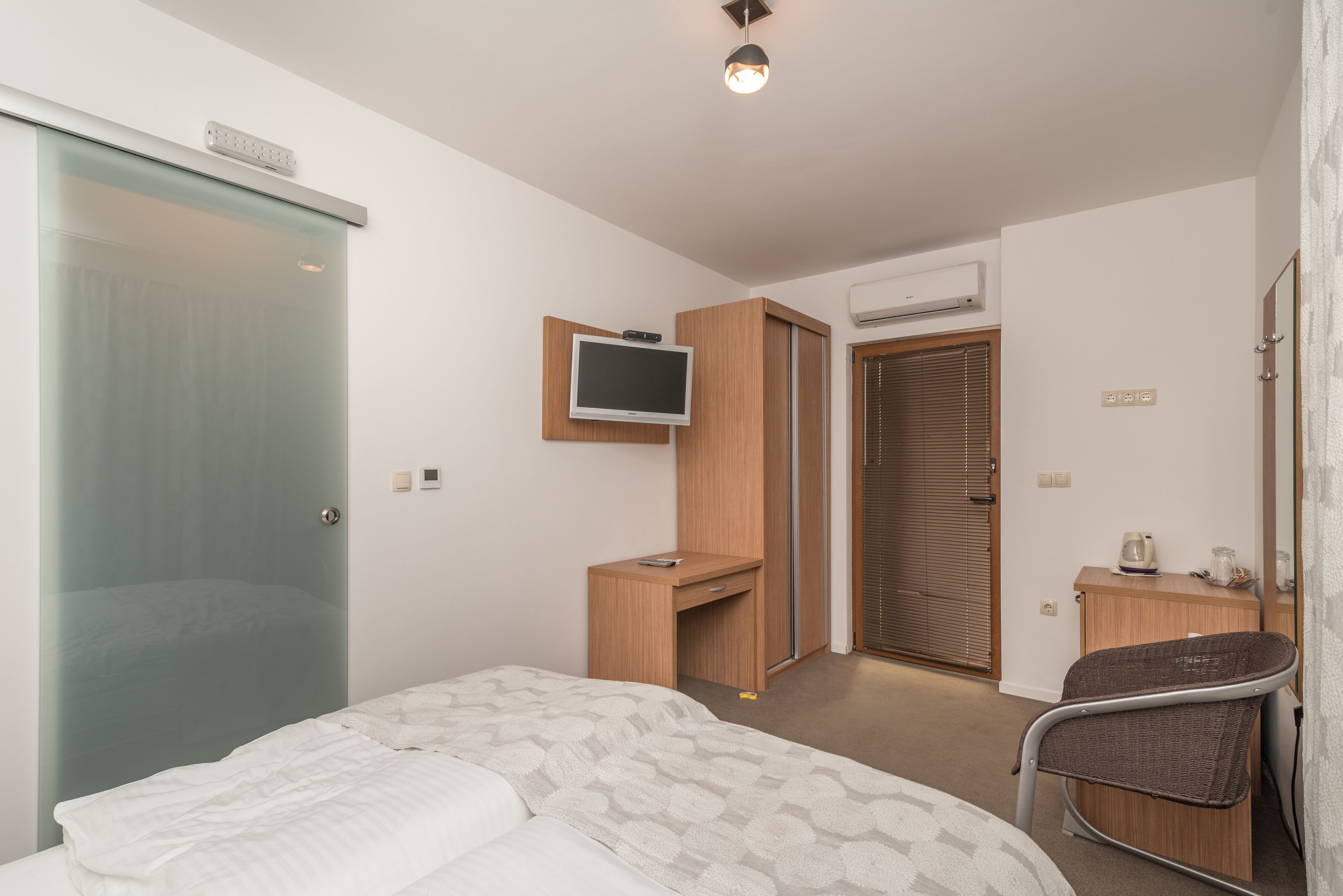 Une chambre d’hôtel équipée d’un lit, d’un bureau, d’une chaise, d’une télévision et d’un appareil de climatisation.
