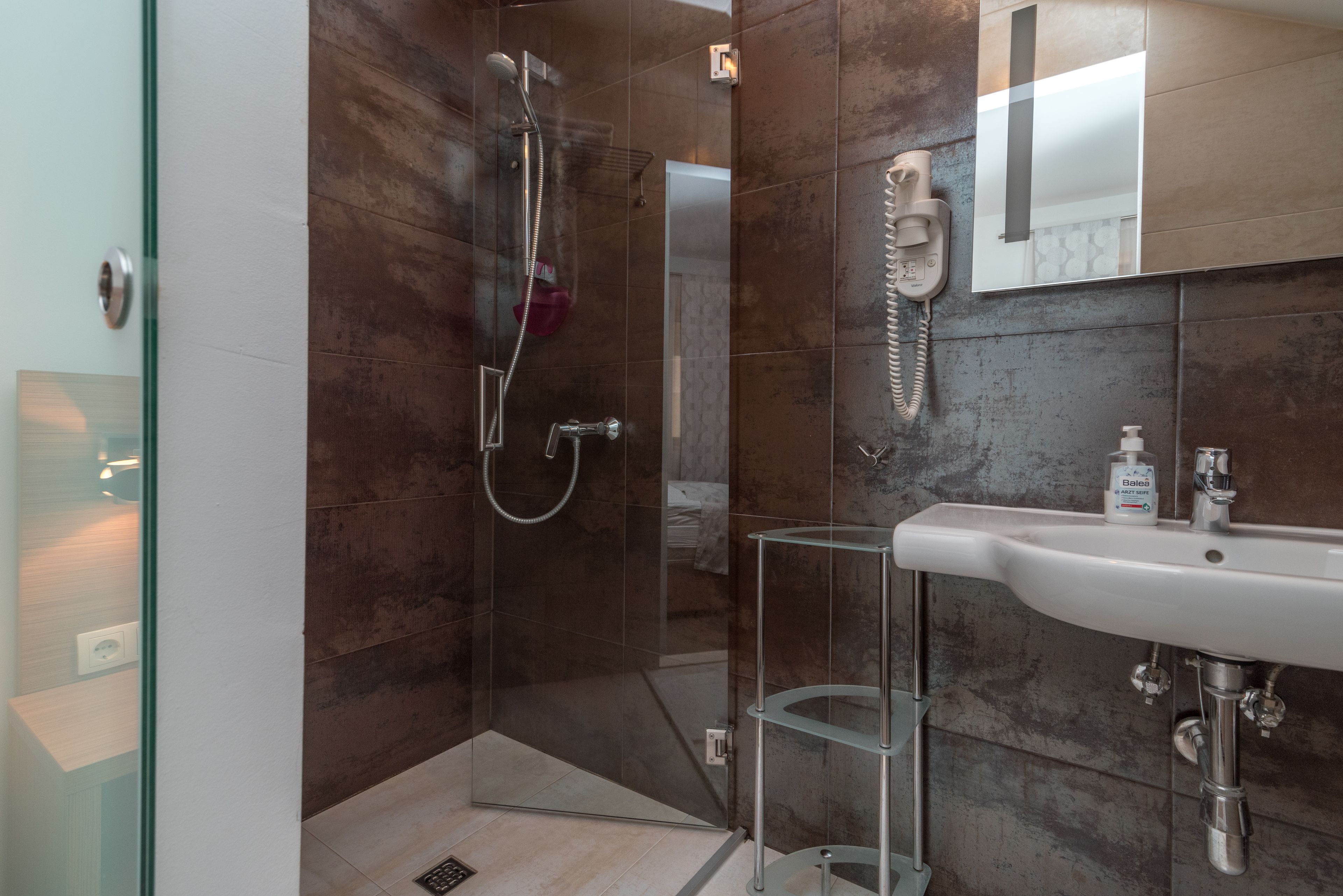 Ein modernes Badezimmer mit Duschkabine aus Glas, integriertem Waschbecken und Spiegel darüber.