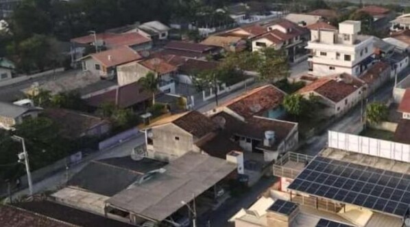 A residential area with houses, some with solar panels, and a road. - Pousada Dois Corações (Penha)