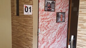A hotel entrance with a numbered door, a wall-mounted light, and a door mat. - Pousada Dois Corações (Penha)