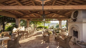 An outdoor patio with wooden beams, wicker furniture, a fireplace, and a view of the landscape.
