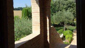 An arched stone corridor with a view of a garden and trees.