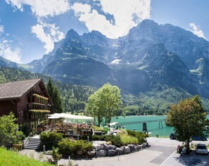 A mountain lodge with a dining area and a view of a lake and mountains. - Hotel Rhodannenberg AG (Glarus)
