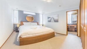 Un dormitorio moderno con una cama grande, un espejo redondo y vista al baño.