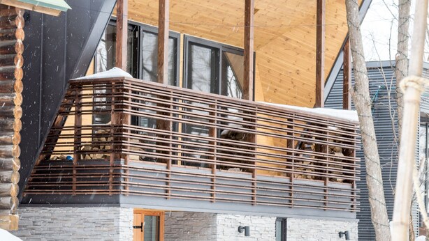 Un edificio moderno con balcón de madera y paredes de piedra.