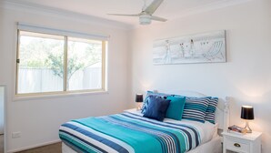 A bedroom with a large bed, a ceiling fan, a window, and a wall-mounted artwork. - Gold Coast Theme Park Villa (Coomera)