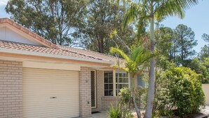A single-story house with a garage, a small porch, and a palm tree in the front yard. - Gold Coast Theme Park Villa (Coomera)