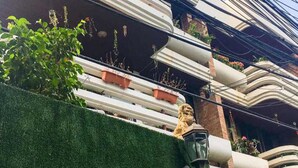 A building facade with the name "NEGO" and the number "45/5" on a green wall. There are multiple balconies with plants and a statue. - Nego Home (Bangkok)