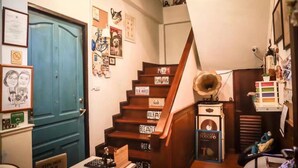 A staircase with vintage signs, a gramophone, and various wall decorations in a cozy room. - Nego Home (Bangkok)