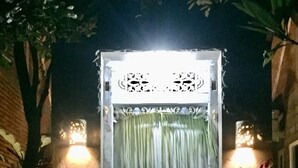 A well-lit entrance with a decorative gate, two wall-mounted lights, and a statue on either side. - Pranajaya Villa (Tejakula)