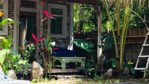 A swimming pool with a wooden deck, surrounded by tropical plants and a stone wall. - Pranajaya Villa (Tejakula)