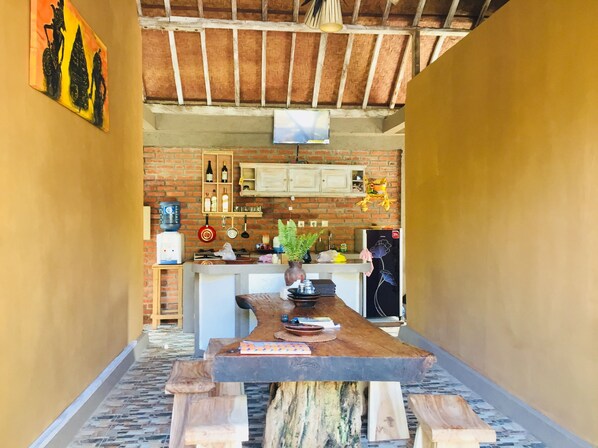 A rustic kitchen with exposed brick walls, wooden beams, and a central island with a sink and countertop.