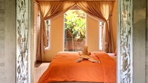 A room with a bed under a canopy, a window with curtains, and a view of greenery outside. - Pranajaya Villa (Tejakula)