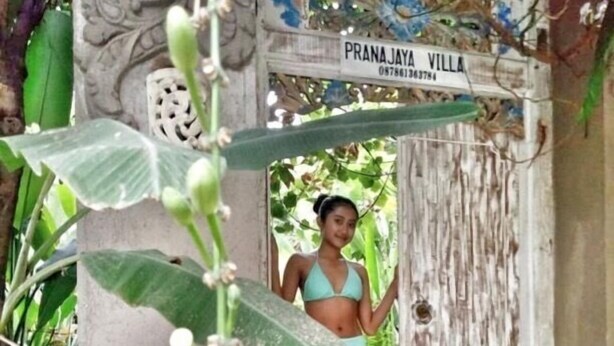 A woman in a bikini standing in a doorway with a sign reading "PRANA JAYA VILLA." - Pranajaya Villa (Tejakula)