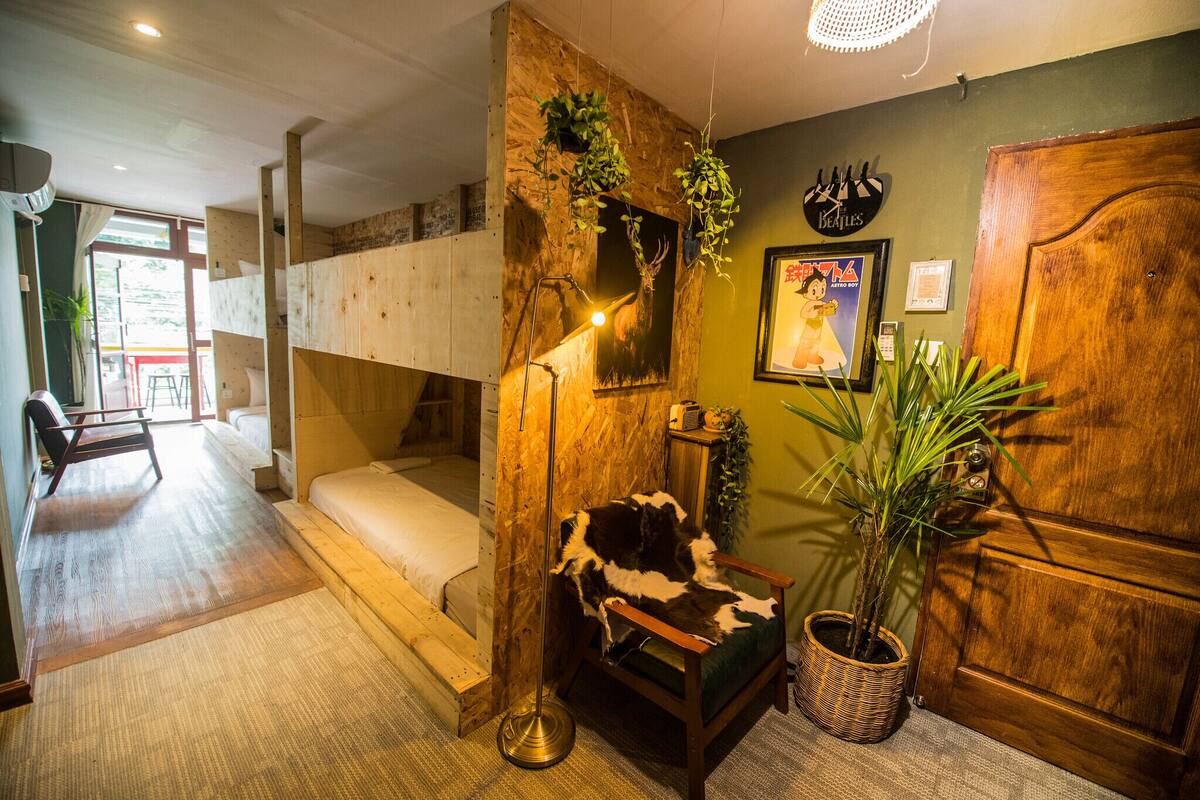 A room with a bunk bed, a chair with a fur seat, a lamp, and a potted plant.