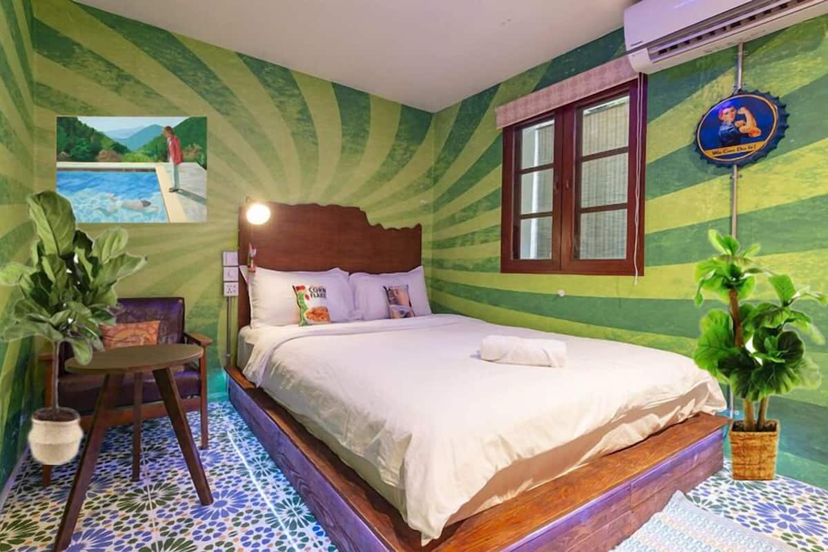 A bedroom with a bed, a nightstand, a chair, and a wall-mounted air conditioner.