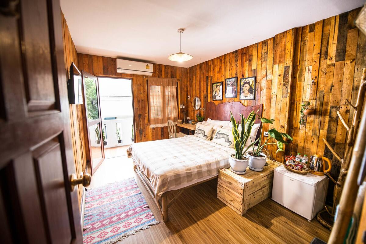 A wooden-paneled bedroom with a bed, bedside tables, a radiator, and a window.
