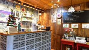 A restaurant interior with a wooden ceiling, a decorated Christmas tree, a menu board, and various kitchen appliances. - Nego Home Ancient Hotel (Bangkok)