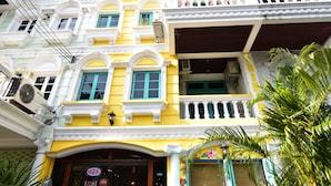 A multi-story building with a yellow facade, white trim, and green shutters. - Nego Home Ancient Hotel (Bangkok)
