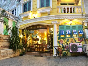 A building with a traditional facade, a balcony with white balustrades, and a sign indicating the establishment is open. - Nego Home Ancient Hotel (Bangkok)